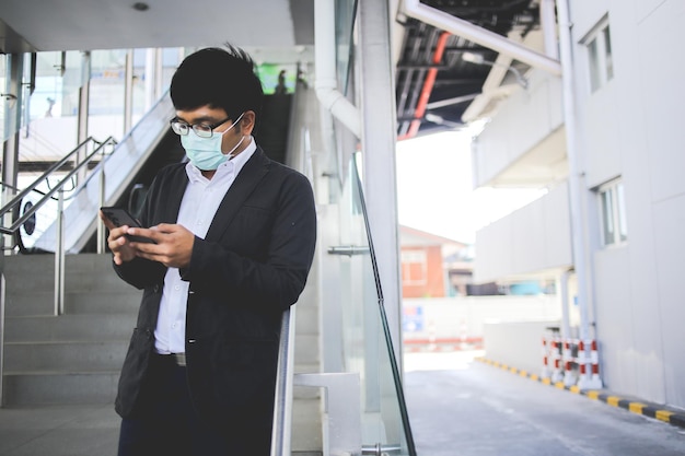 Freelancer masculino asiático usando máscara cirúrgica indo trabalhar de manhã no metrô