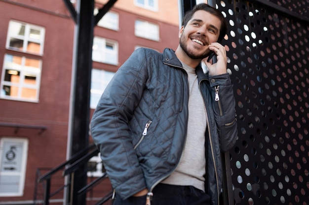 Freelancer masculino europeu de sucesso falando ao telefone na rua