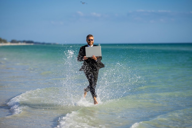 Freelancer de negocios de verano en el hombre de negocios de la playa del mar de verano en traje de neopreno en negocios locos de agua de mar