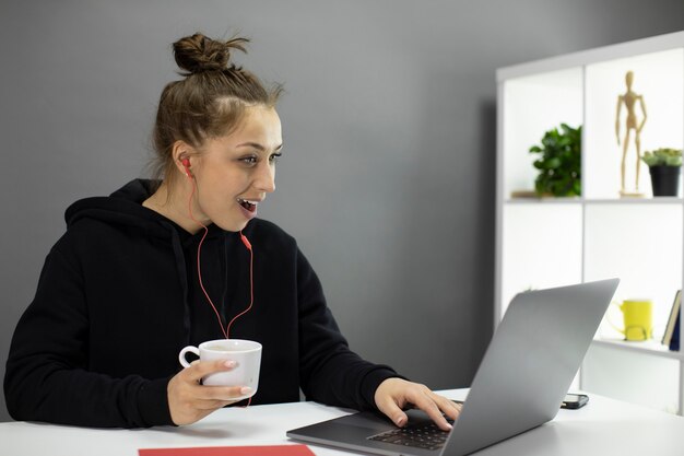 Freelancer positivo jovem com café na mão assistindo o blog de vídeo