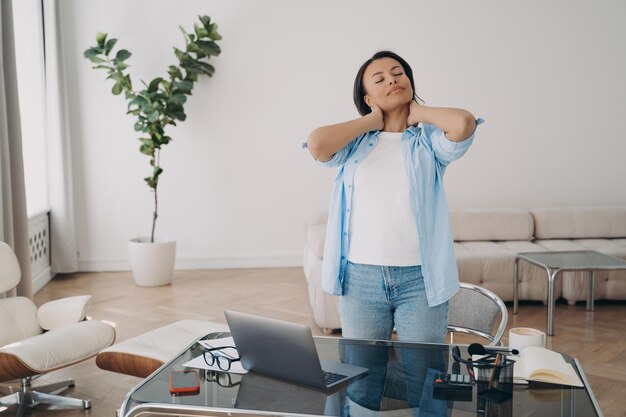 Freelancer se relaja después del trabajo con los ojos cerrados Mujer de negocios masajeando el cuello y sonriendo