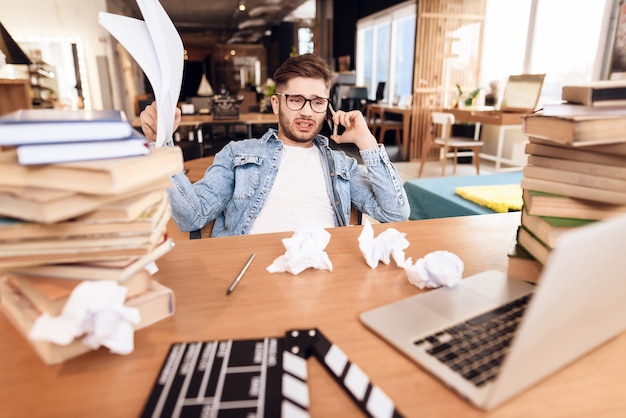 Freelancer, sentado na mesa, rodeada de livros.