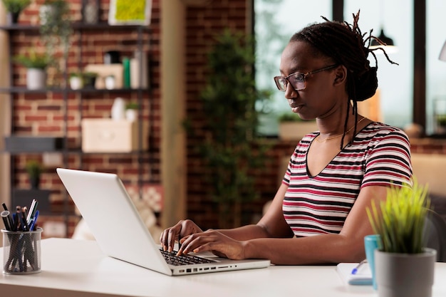 Freelancer trabalhando, digitando no teclado do laptop no escritório em casa. Jovem funcionário remoto escrevendo mensagem no teclado do computador, conversando nas mídias sociais, navegando na internet, sentado na mesa