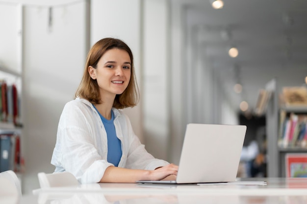 Freelancer usando laptop escribiendo trabajando en línea sentado en el lugar de trabajo. Estudiante sonriente estudiando