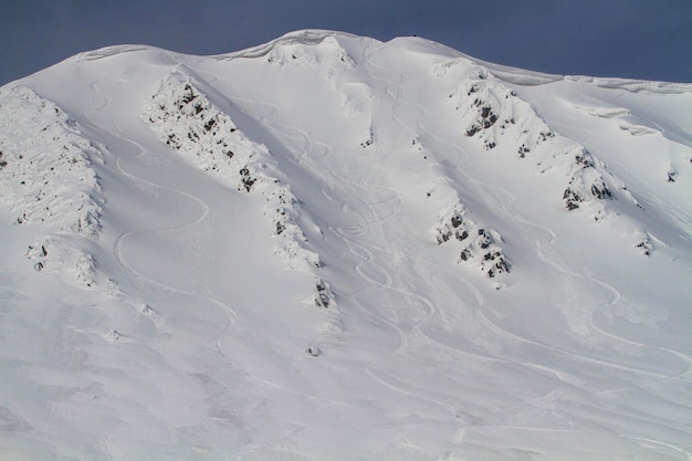 Freeride-Downhill auf einem steilen und schneebedeckten Hang neben einem Schneegesims im Hochgebirge