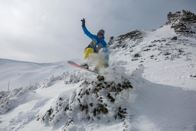 Freeride-Downhill-Snowboarden in den schneebedeckten Bergen zwischen Felsen Winter-Freeride-Extremsport