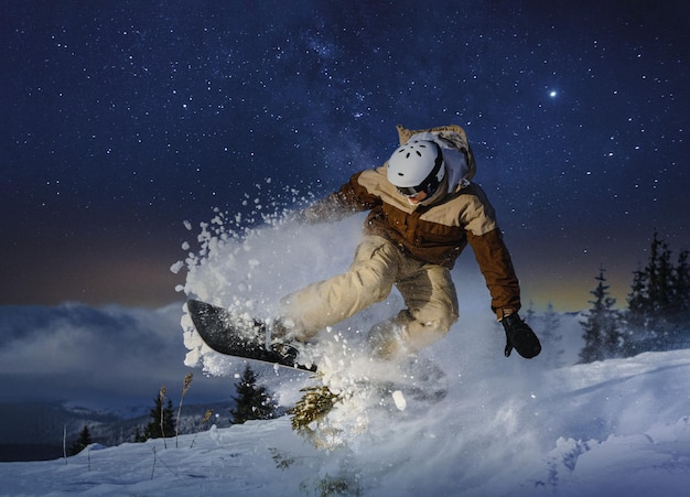 Freestyle-Snowboarder springt mit Snowboard unter den Sternenhimmel