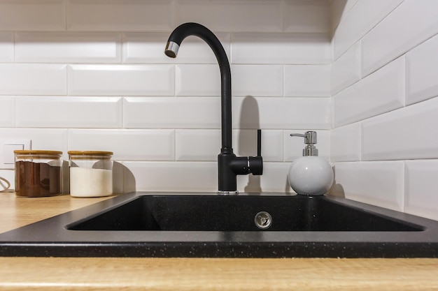 Fregadero de agua negra con grifo y dispensador de jabón en la costosa cocina tipo loft