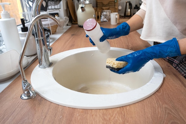 Fregadero de limpieza en la cocina Mano en guantes y esponja detergente polvo seco acogedor interior de la casa restauración orden limpieza desinfección