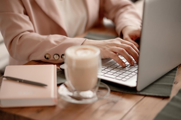 Freiberufler arbeitet am Computer im Café Mädchen Geschäftsfrau in beige rosa Jacke tippt auf dem Keybo