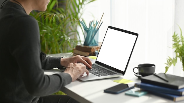 Freiberufler des jungen Mannes, der im bequemen Arbeitsplatz sitzt und Laptop-Computer verwendet.