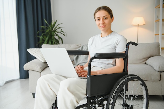 Freiberufler im Rollstuhl mit Laptop in der Nähe von Notizbuch und Papieren auf dem Tisch