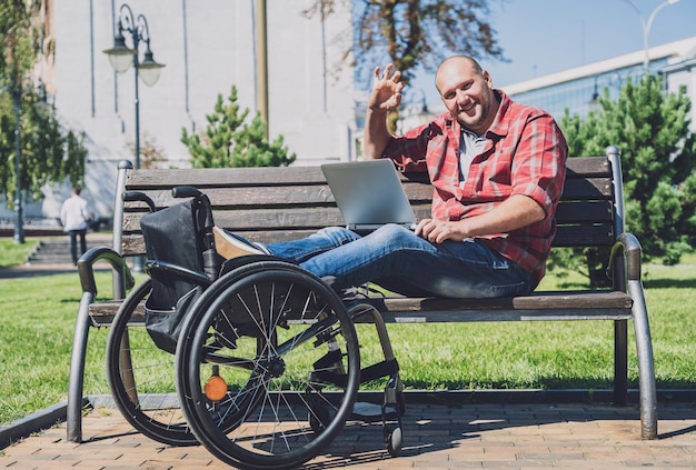 Foto freiberufler mit einer körperlichen behinderung, der im park im rollstuhl arbeitet