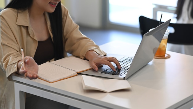 Freiberuflerin der jungen Frau, die im Café sitzt und mit Laptop-Computer arbeitet.