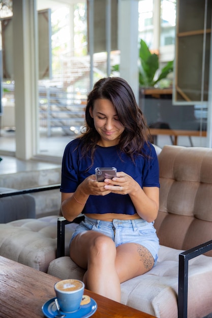 Freiberuflerin der jungen Frau, die mit Handy arbeitet, sitzt sie am Tisch