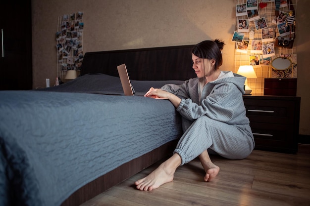 Freiberuflerin, die zu Hause am Laptop arbeitet und auf dem Boden sitzt Laptop auf dem Bett