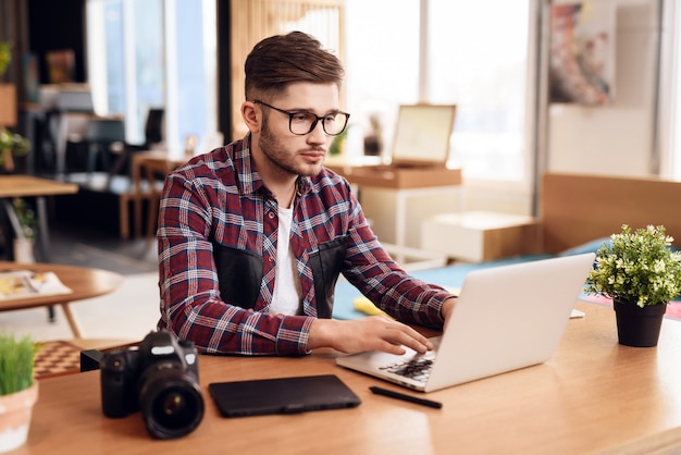 Freiberuflermann, der am Laptop sitzt am Schreibtisch schreibt.