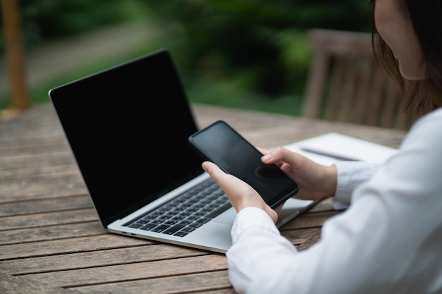 Freiberufliche Frau, die Smartphone verwendet, nachdem sie mit Laptop auf dem Tisch gearbeitet hat Geschäftsfrau, die mit dem Mobiltelefon sucht oder soziale Medien nutzt oder online einkauft oder auf Lager Smartphone-Gesprächskonferenz