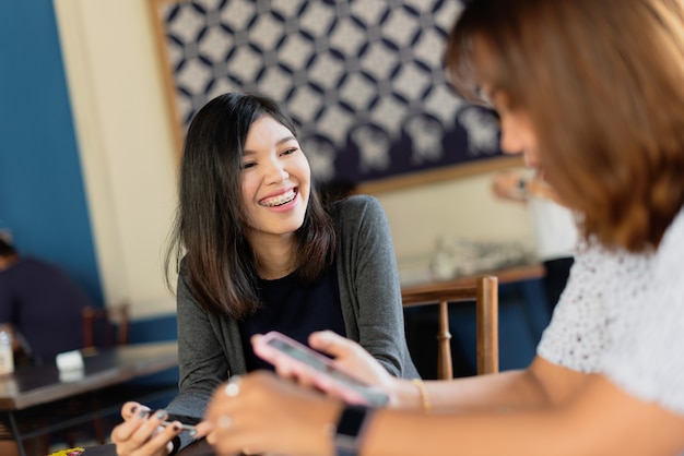 Freiberufliche Sitzung der asiatischen Mädchen mit Kollegen am coffeeshop.