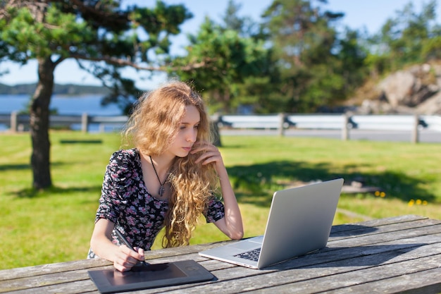 Freiberufliches Mädchen, das am Laptop in der Natur und in wunderschönen Landschaften arbeitet