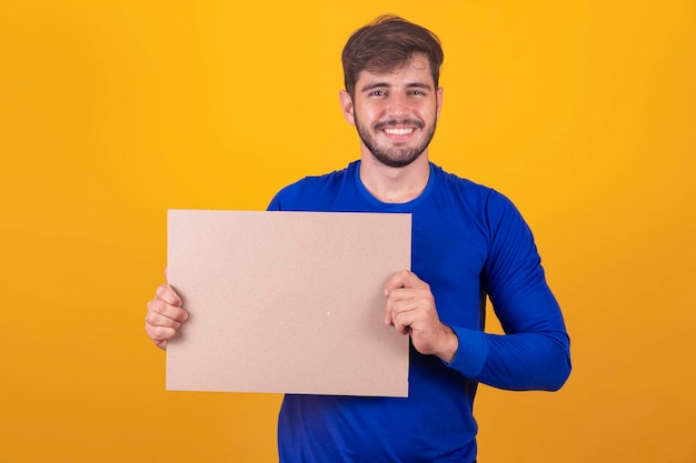 Freier Platz für Werbung Fröhlicher kaukasischer Mann, der auf eine leere weiße Tafel auf gelbem Studiohintergrund zeigt