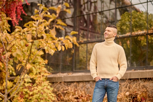 Freiheit. Ein Mann in einem beigefarbenen Rollkragenpullover im Herbstpark