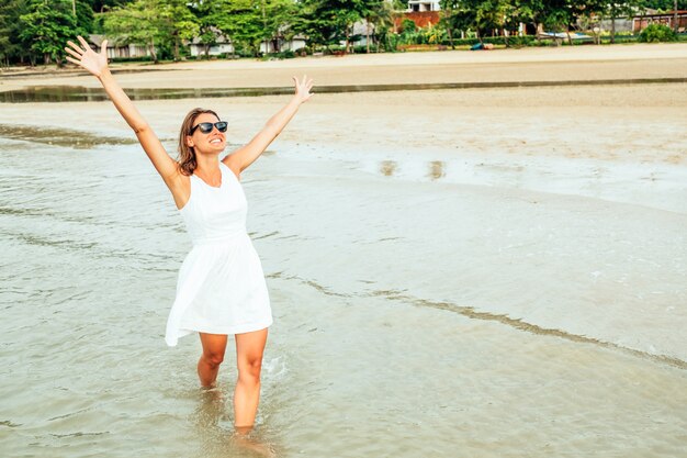 Freiheit glückliche Frau mit erhobenen Armen am Strand am sonnigen Tag