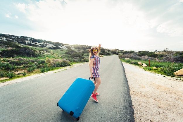 Freiheit, Reisen, Urlaub und Sommerkonzept - Reisende Frau, die mit Koffern auf der Straße geht und lacht