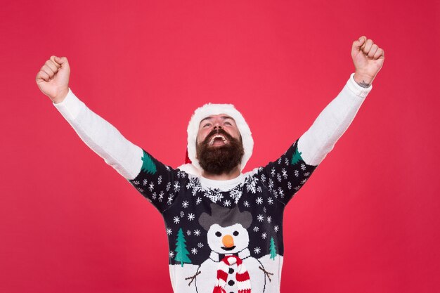 Freiheit und Erfolg spüren. neues jahr glück. frohe weihnachten dir. Spaß haben. glücklicher bärtiger Mann rote Weihnachtsmütze. aufgeregter Hipster lustiger Pullover mit Schneemann. Herzliche Glückwünsche.