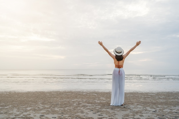 Freiheitsfrau im Bikini, der mit den auf dem Meeresstrand erhobenen Armen geht