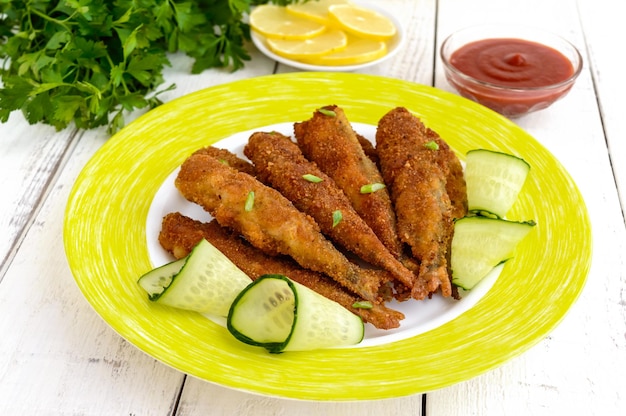 Freír capelán de pescado pequeño en un plato sobre fondo blanco de madera