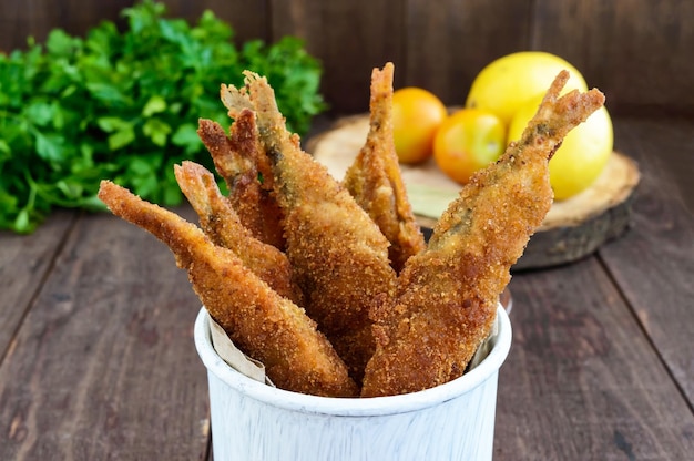 Freír el capelán de pescado pequeño en una taza sobre un fondo de madera oscura Un buen refrigerio para la cerveza