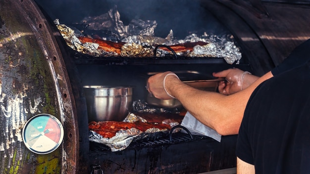 Freír carne en papel de aluminio en una parrilla, cocinero de trabajo. Camión de comida. Comida de la calle