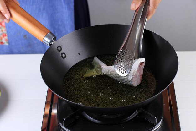 Freír chano (bandeng) en aceite caliente, proceso de cocción entre bastidores para hacer sopa de chano (Pindang Bandeng)