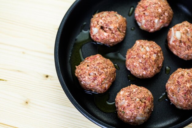 Freír grandes albóndigas italianas caseras en una sartén midium para la cena.