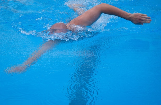 Freistilschwimmen im Schwimmbad. Junger Mann schwimmt in einem Pool im Kraulschwimmen. Männlicher Schwimmer