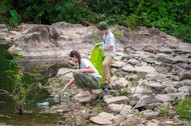 Freiwillige Asiaten und Kinder sammeln Plastikflaschen, die durch den Bach in den Müll fließen