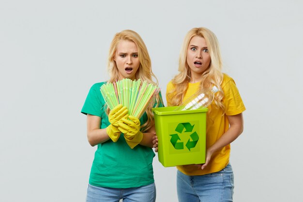 Foto freiwillige freiwillige in gelben und grünen t-shirts und handschuhen sammeln plastikmüll in einem behälter zum recycling.