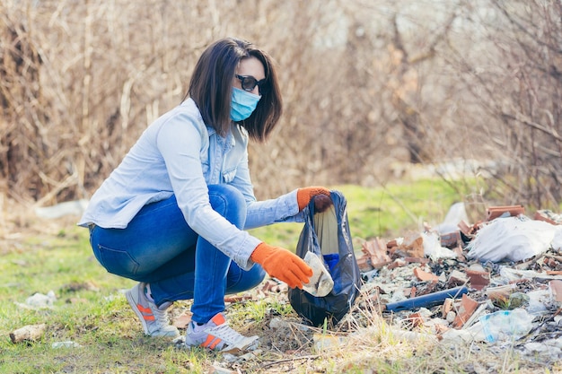 Freiwillige hält eine Tasche mit gesammeltem Plastik in der Hand, um den Wald und den Park vom Müll zu reinigen