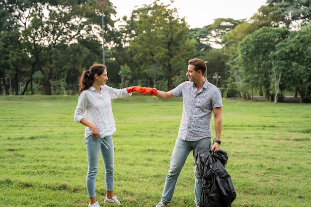 Freiwillige Liebhaberpaare, die Handschuhe tragen, um Müll im Park aufzusammeln, um die Umwelt sauber zu halten