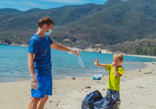 Freiwillige Paradies Strand Sand Lazur Meer Mann Junge Müll in schwarze Tasche aufheben Sohn weigert sich, blaue Gesichtsmaske zu tragen, weil müde schwer atmen Neue Ära in der Maske Natürliche Kindererziehung