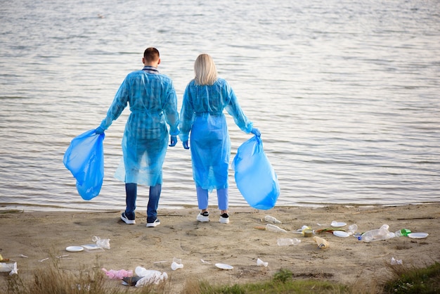 Freiwillige sammeln Plastikflaschen in Müllsack, Ökologie, Natur, Umweltverschmutzung, Müll, Pflege, Freiwilligenarbeit für wohltätige Zwecke, Gemeinschaftsumgebung.