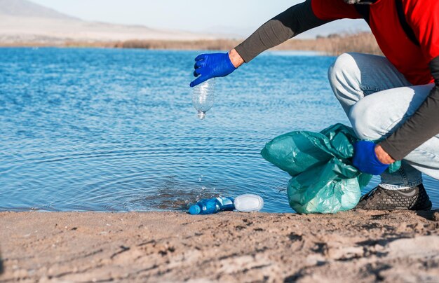 Freiwilliger sammelt Plastikmüll am Strand hand viewx9