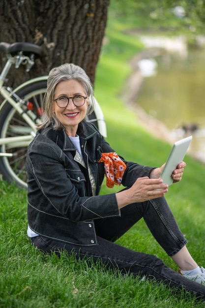 Foto freizeit. eine frau, die in der nähe des flusses sitzt und sich online etwas ansieht