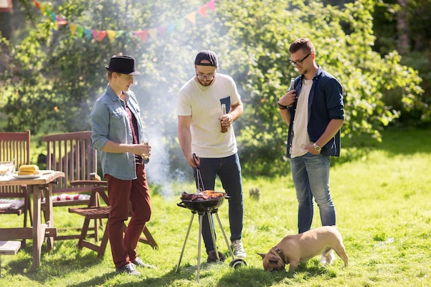 Freizeit-, Essens-, Menschen-, Freundschafts- und Feiertagskonzept - glückliche Freunde, die Fleisch auf dem Grill kochen und Bier auf einer Sommerparty im Freien trinken