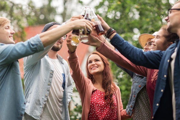 Foto freizeit-, feiertags-, menschen-, wiedersehens- und feierkonzept - glückliche freunde, die gläser anstoßen und bei der sommergartenparty feiern