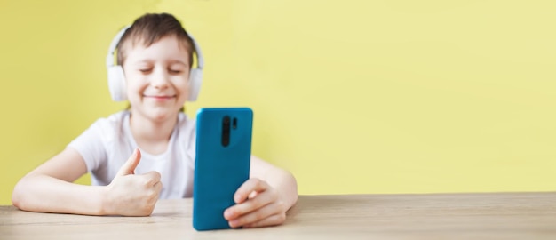 Freizeit Kinder Technologie und Menschen Konzept lächelnder Junge mit Smartphone und Kopfhörer