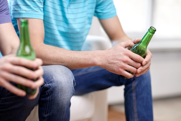 Foto freizeit-, menschen- und alkoholkonzept - nahaufnahme männlicher freunde, die zu hause bier trinken