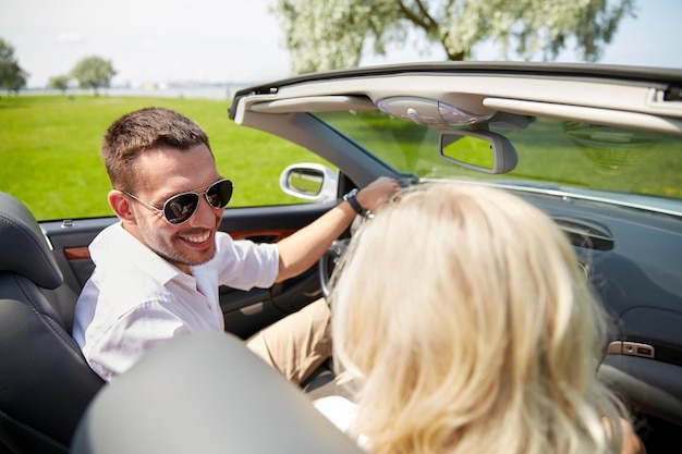 Freizeit, Roadtrip, Dating, Paar- und Personenkonzept - glücklicher Mann und Frau, die im Cabriolet-Auto im Freien fahren