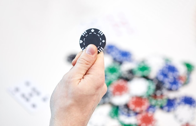 Freizeit, Spiele, Glücksspiel und Unterhaltung - Nahaufnahme der männlichen Hand mit Casino-Chip und Spielkarten zu Hause